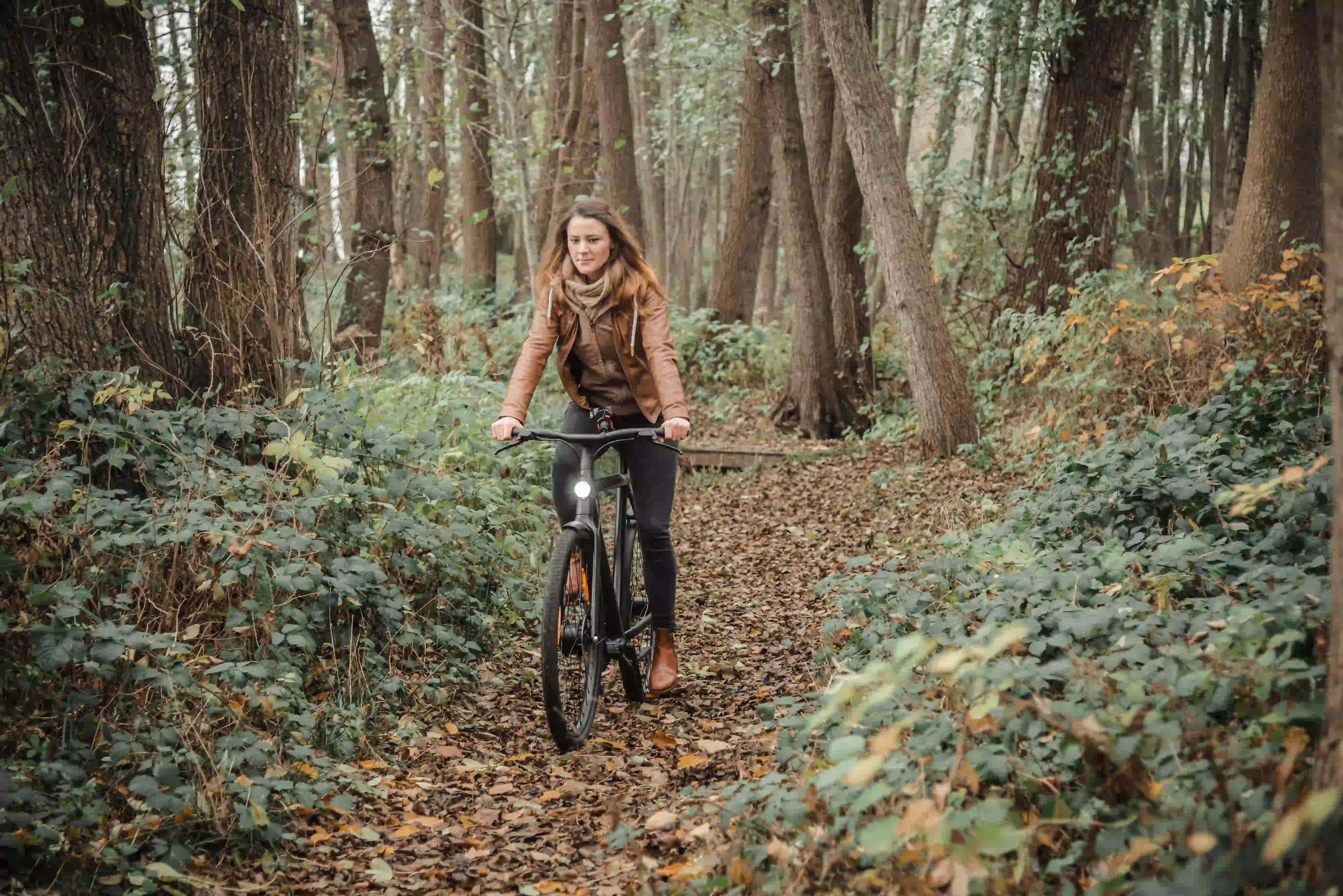 Radfahrerin auf einem Waldweg in den Hüttener Bergen im Herbst