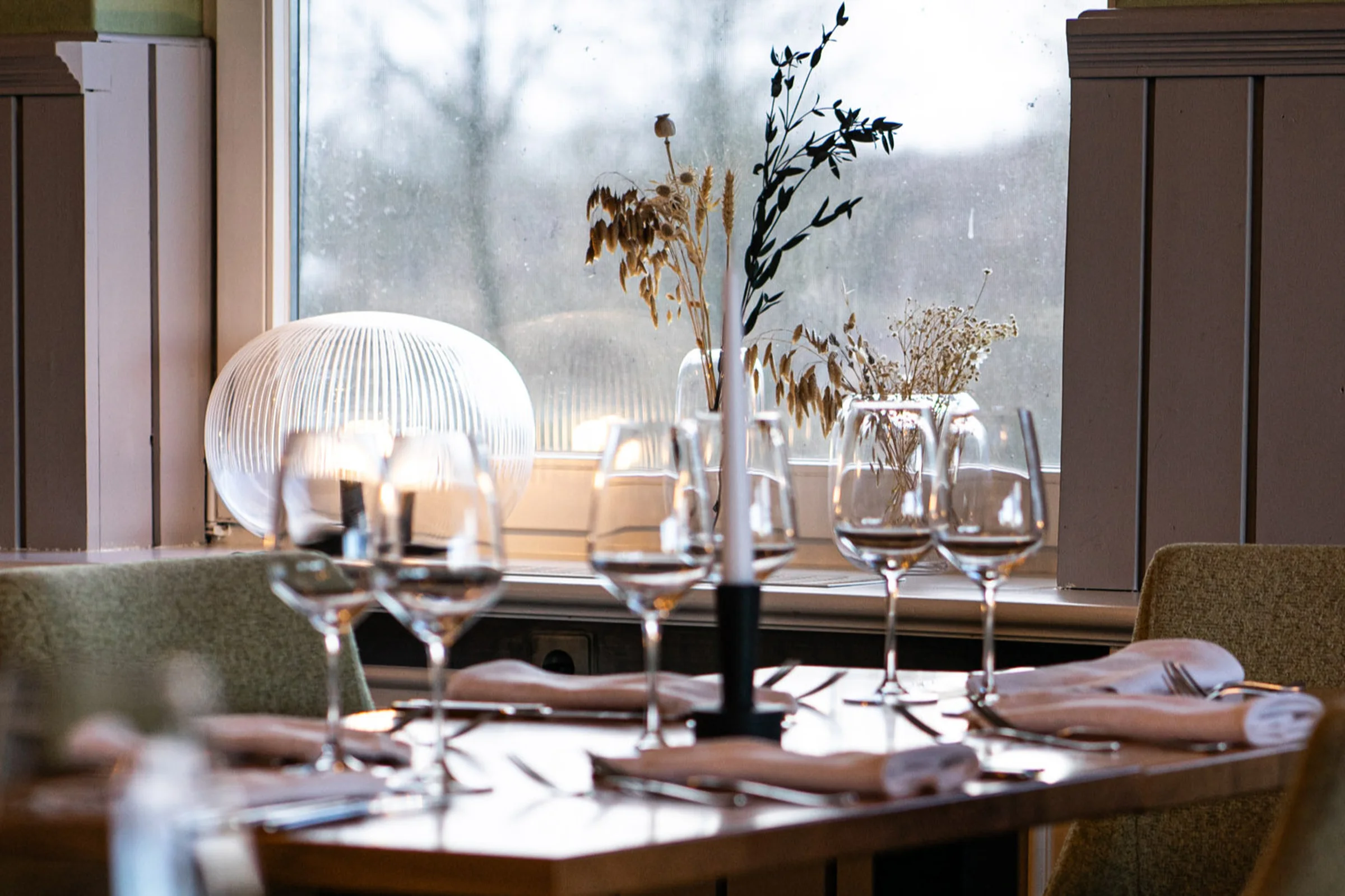 Weihnachtlich gedeckter Tisch mit Kerzen und Weingläsern im Restaurant