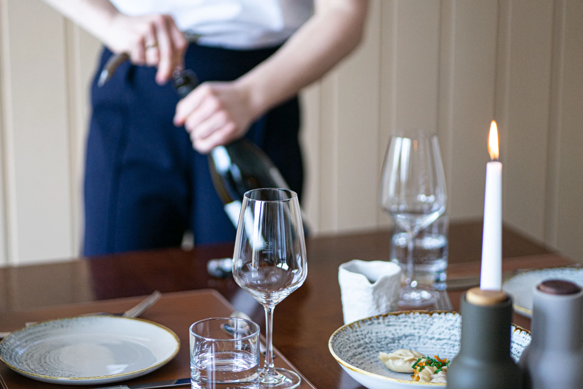 Wein wird am Tisch entkorkt und eingeschenkt