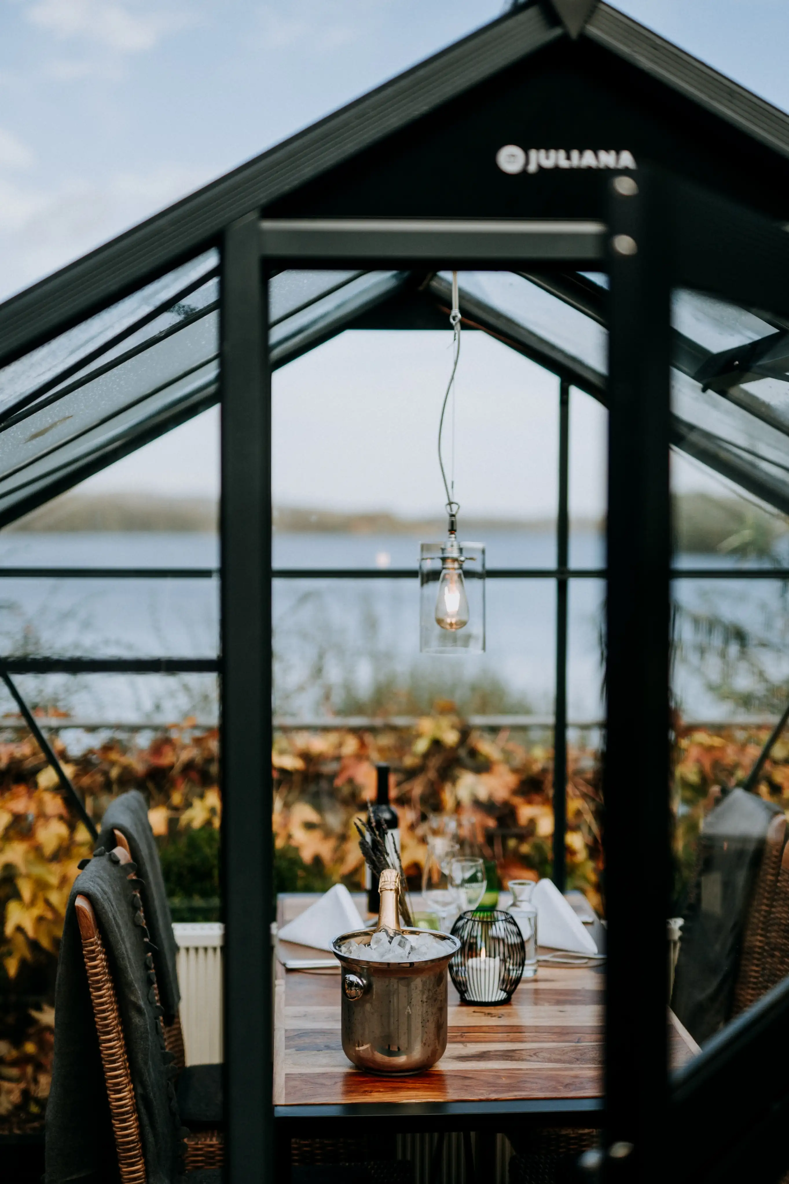 Champagnerglas im Glashaus mit Blick auf den Bistensee