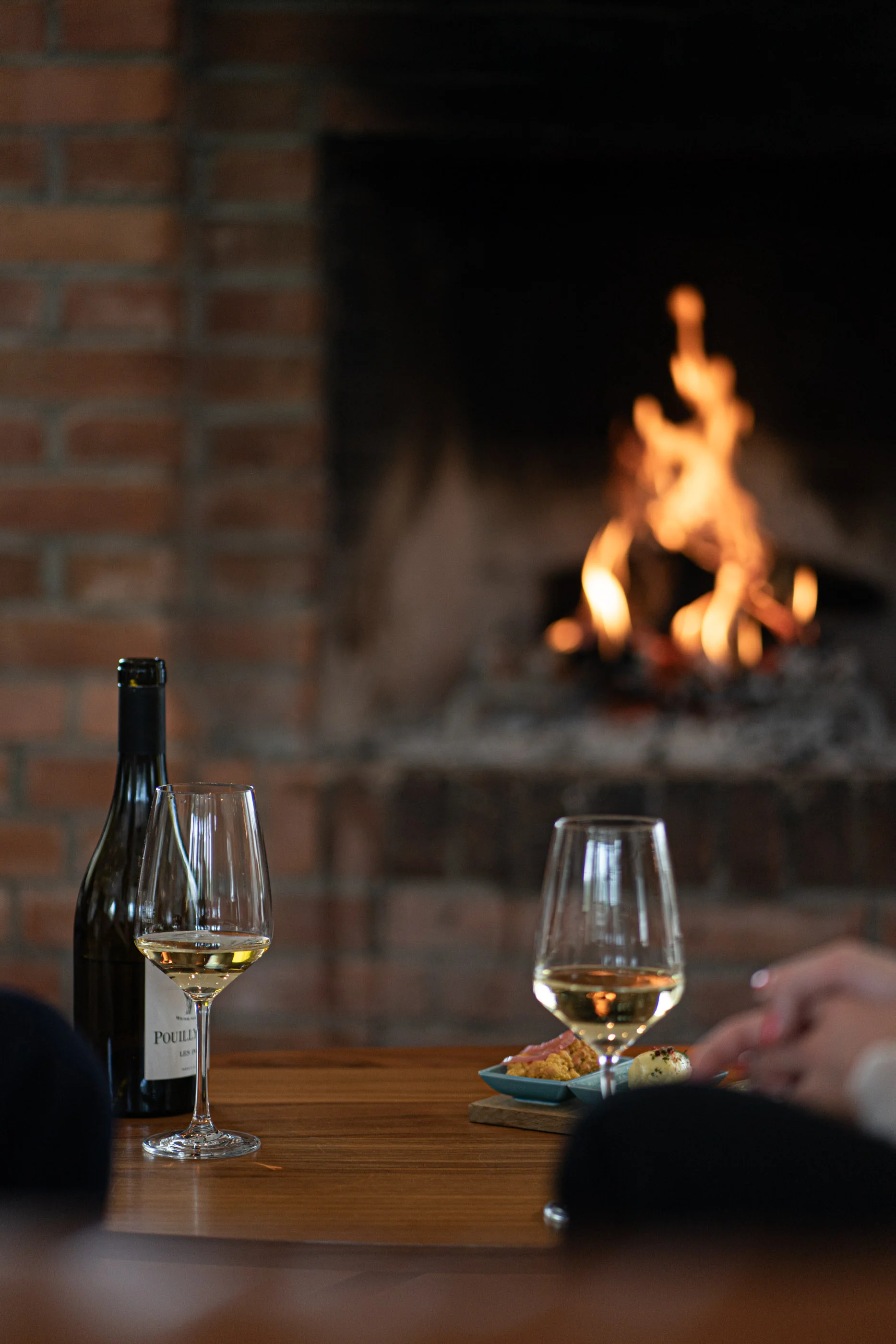Offener Kamin in der Lobby mit Feuer und einem Glas Wein