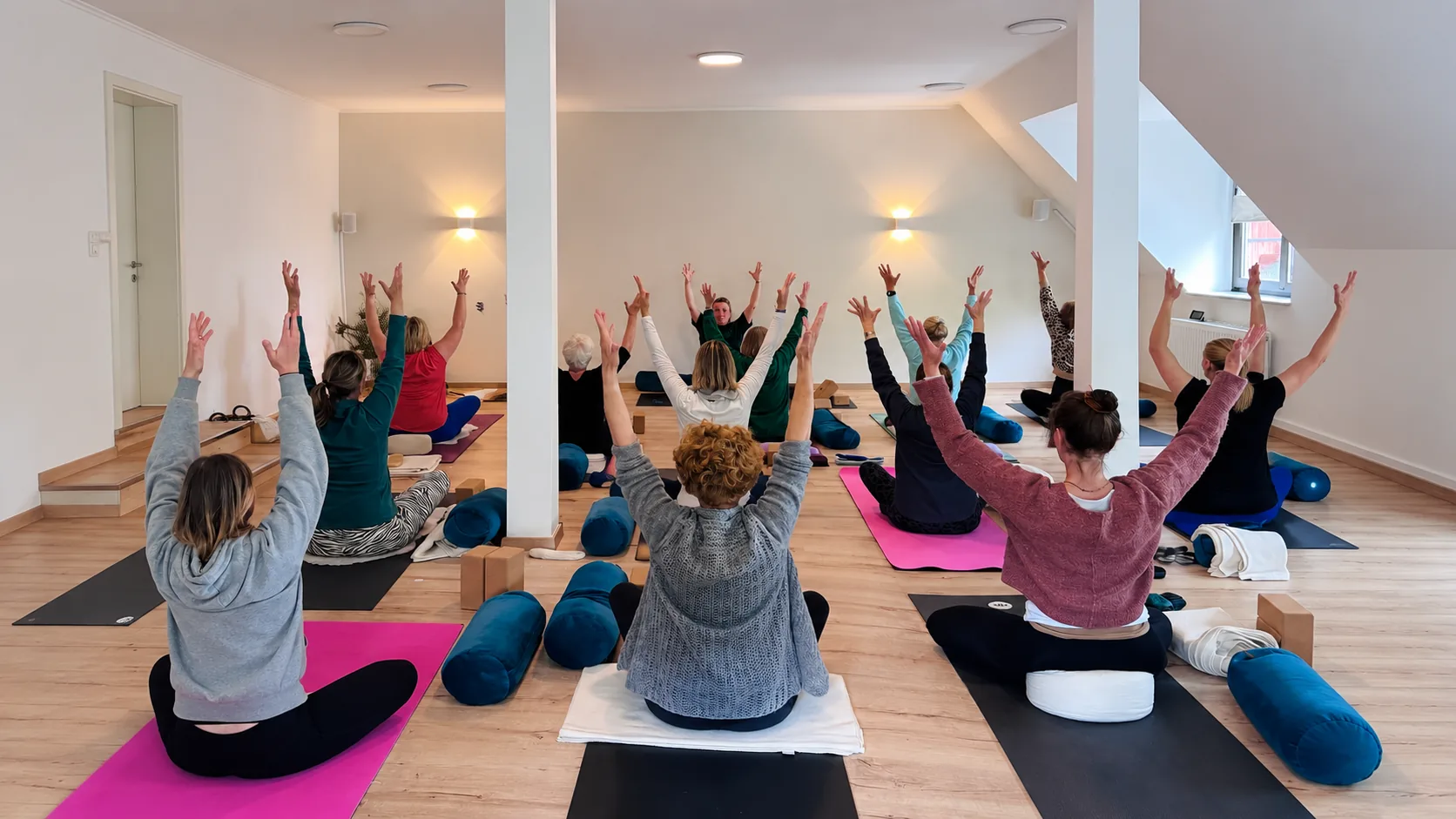 Yogagruppe beim Üben, Arme nach oben gestreckt