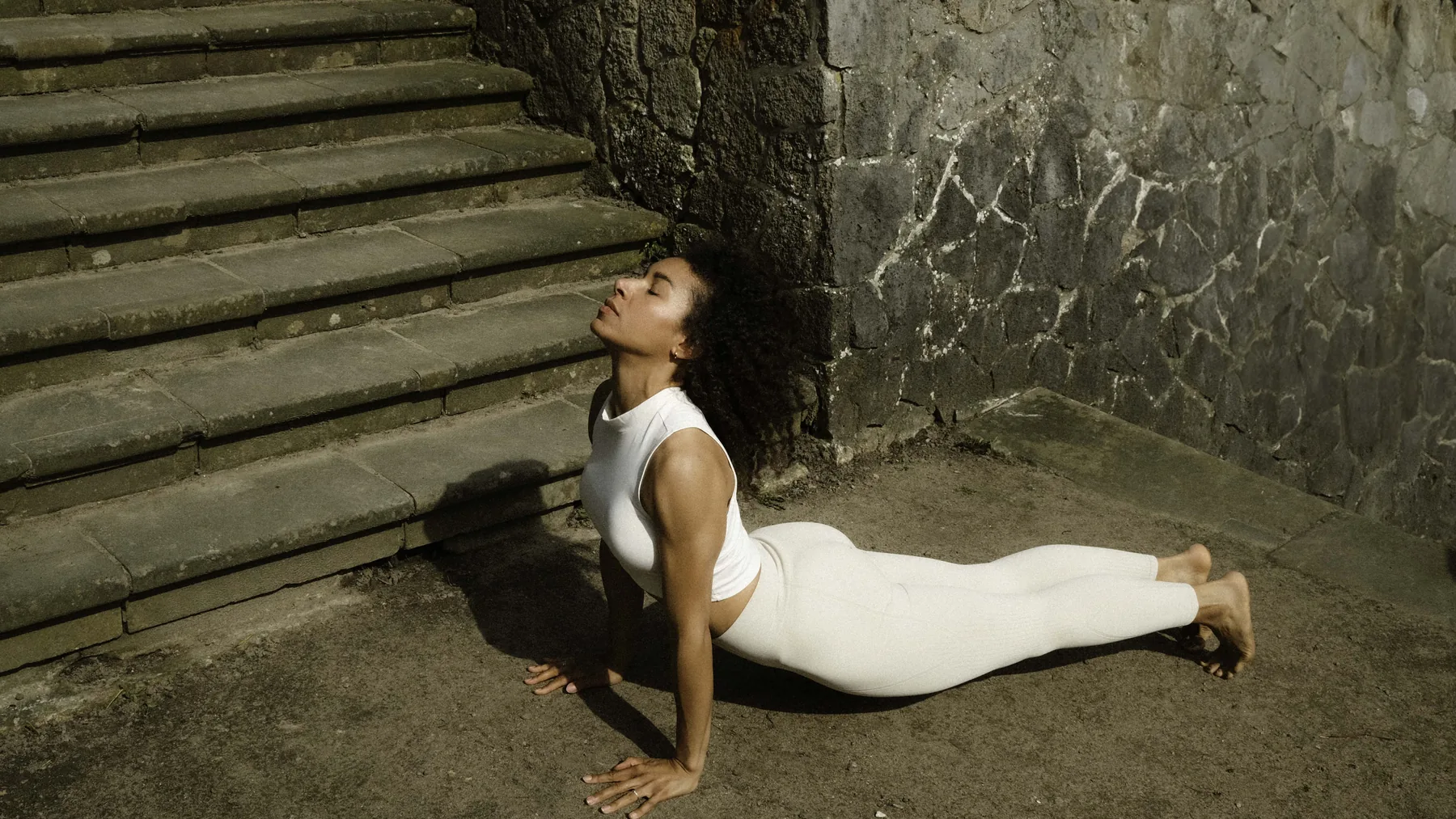Felicitas Ntomchukwu in einer Yogahaltung auf alten Steinstufen