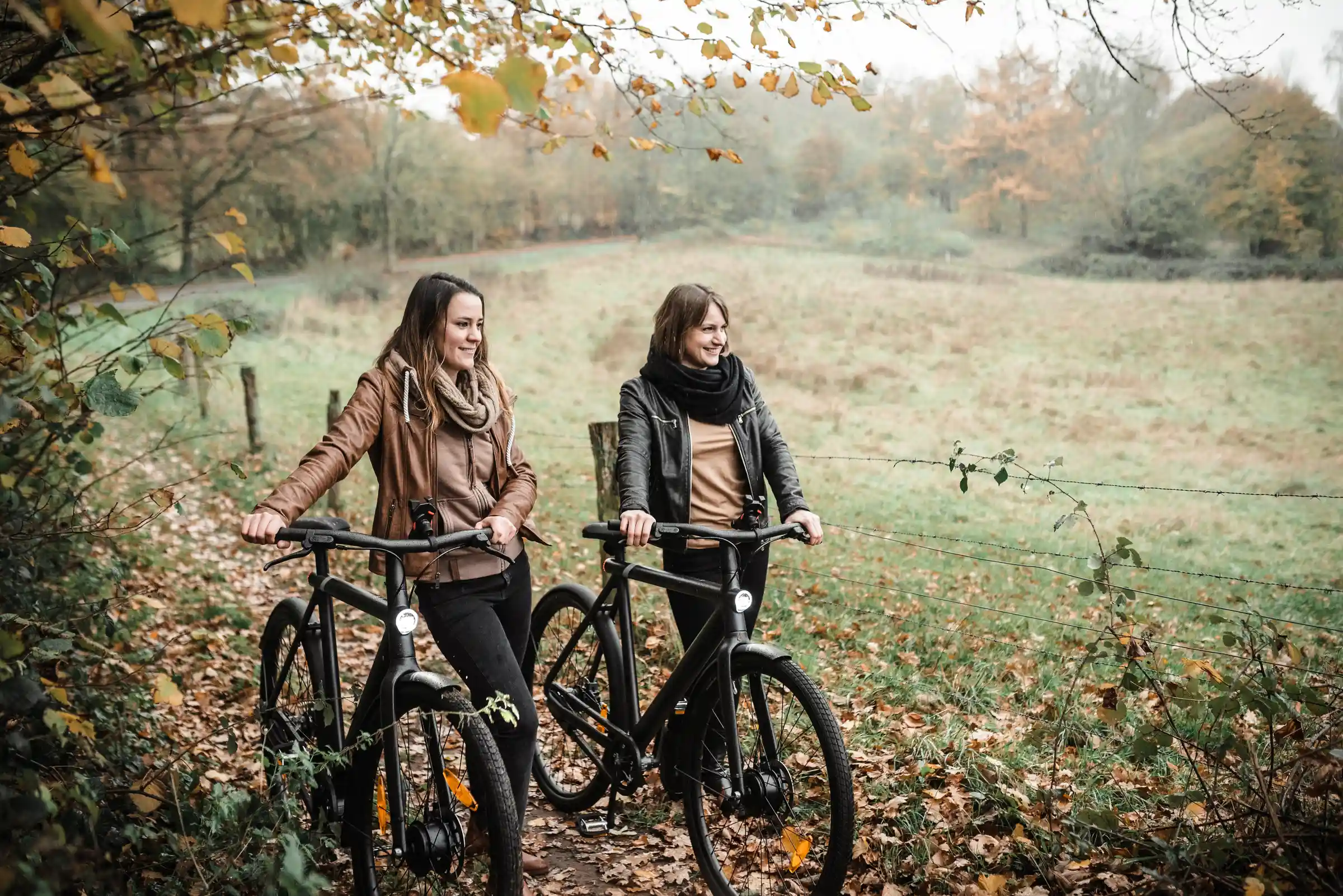 Zwei Frauen mit Fahrrädern im herbstlichen Wald bei den Hüttener Bergen