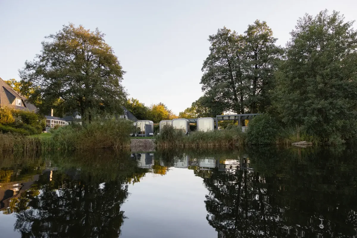 Die Saunen des RAUS. vom Wasser aus, gespiegelt im Bistensee im Abendlicht