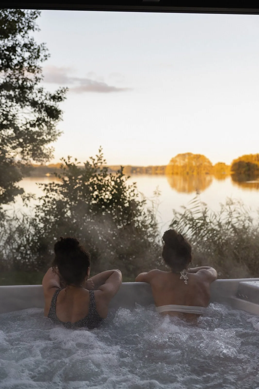 Zwei Freundinnen im Sprudelbad des RAUS. mit Blick auf den Bistensee im Abendlicht