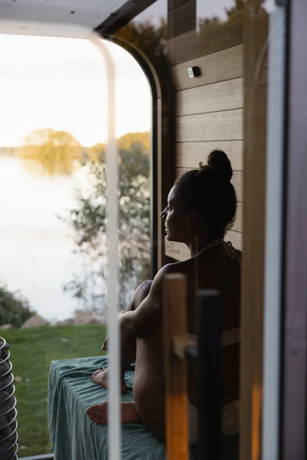 Frau in der Sauna des RAUS. mit Blick auf den Bistensee im Abendlicht